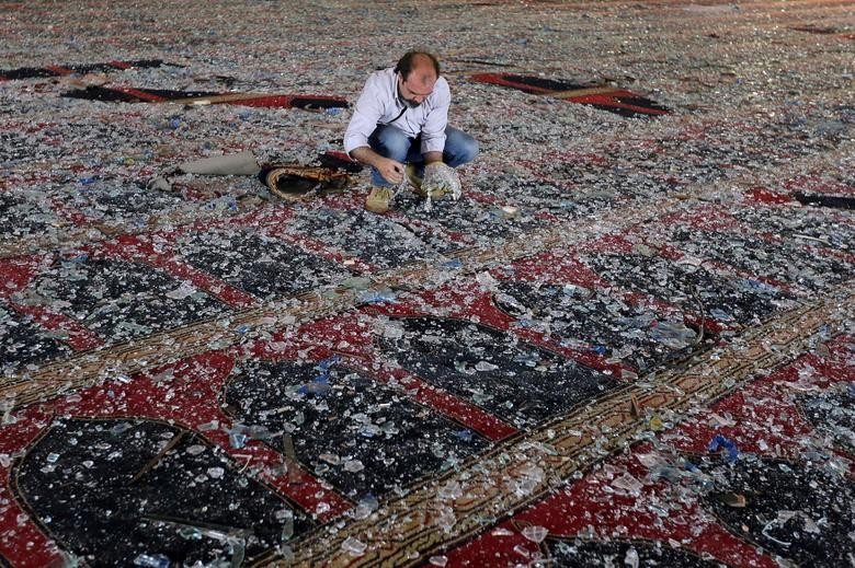 A man removes broken glass scattered on the carpet of a mosque damaged in Tuesday's blast in Beirut, Lebanon August 5, 2020. REUTERS/Aziz Taher
